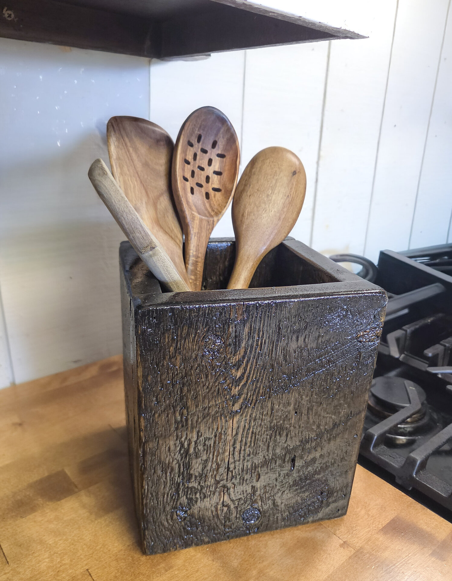 Handmade rustic wooden kitchen utensil holder with spoons and spatulas, crafted from reclaimed Wyoming wood
