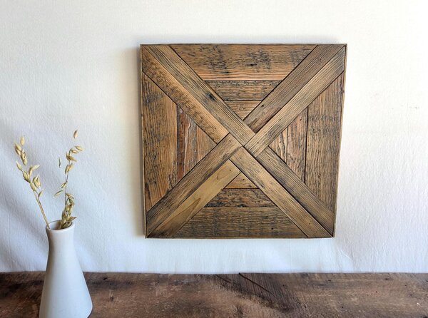 May include: A square wooden wall art piece featuring a geometric pattern of reclaimed wood planks arranged in a crisscross design. The wood displays various brown tones with visible grain, knots, and weathered textures throughout the surface.